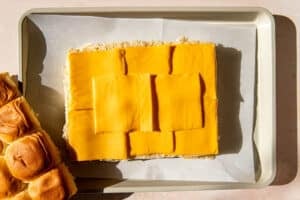 rolls with cheese on top on a parchment paper lined baking sheet.