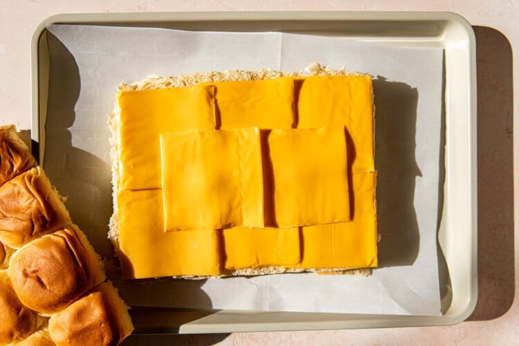 rolls with cheese on top on a parchment paper lined baking sheet.