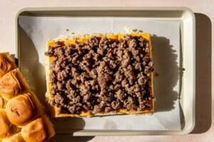 rolls with sausage and cheese on top on a parchment paper lined baking sheet.