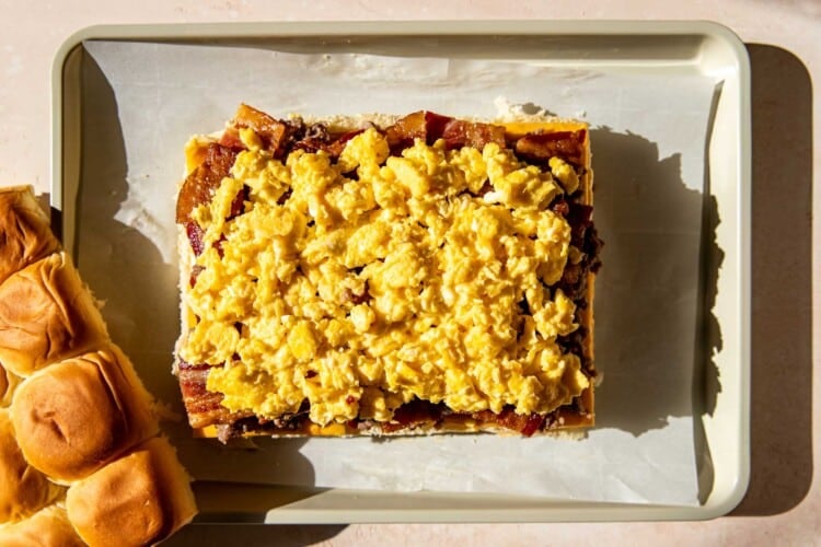 rolls with bacon and eggs on a parchment paper lined baking sheet.