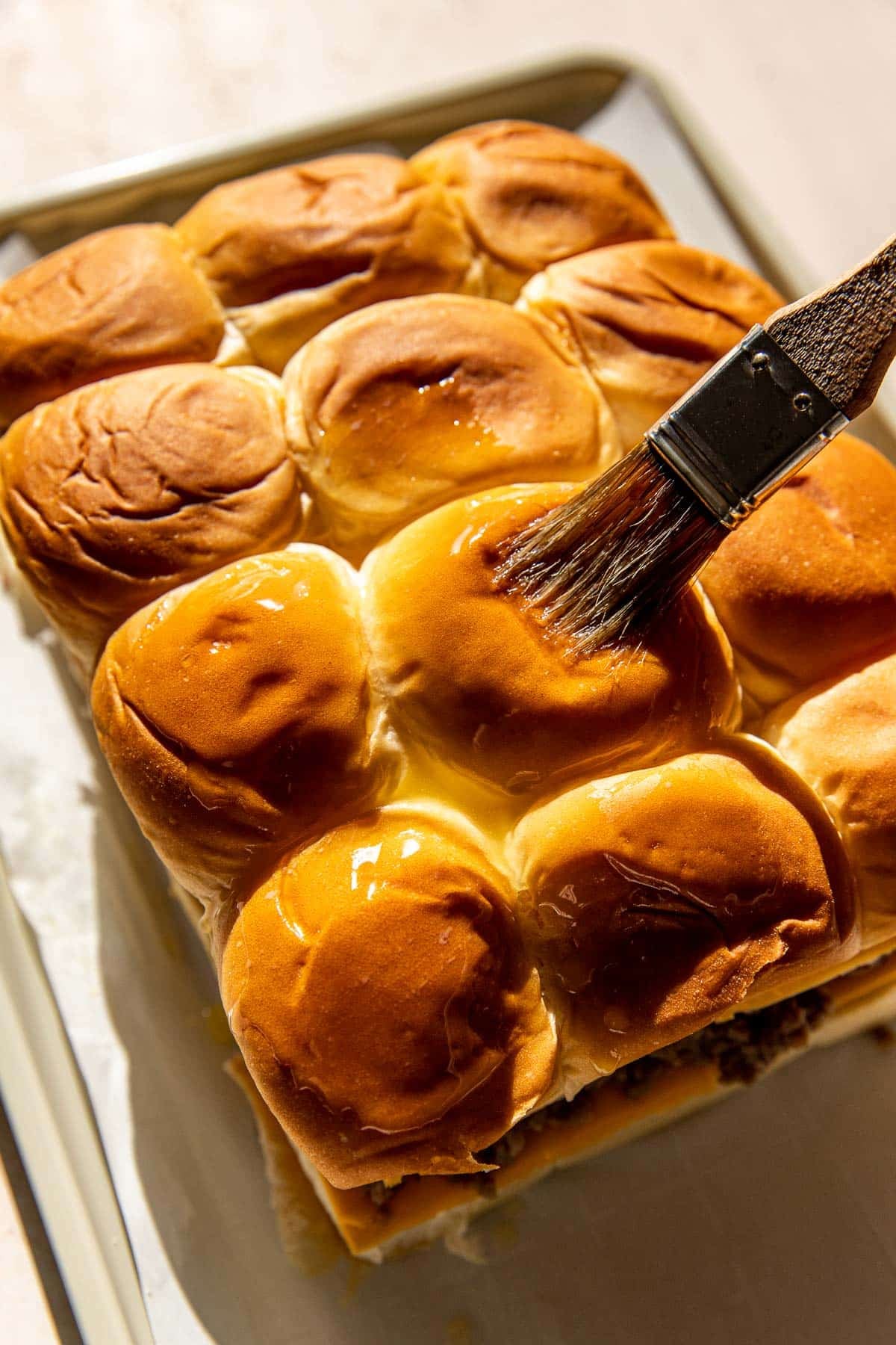 a brush brushing butter on rolls. 