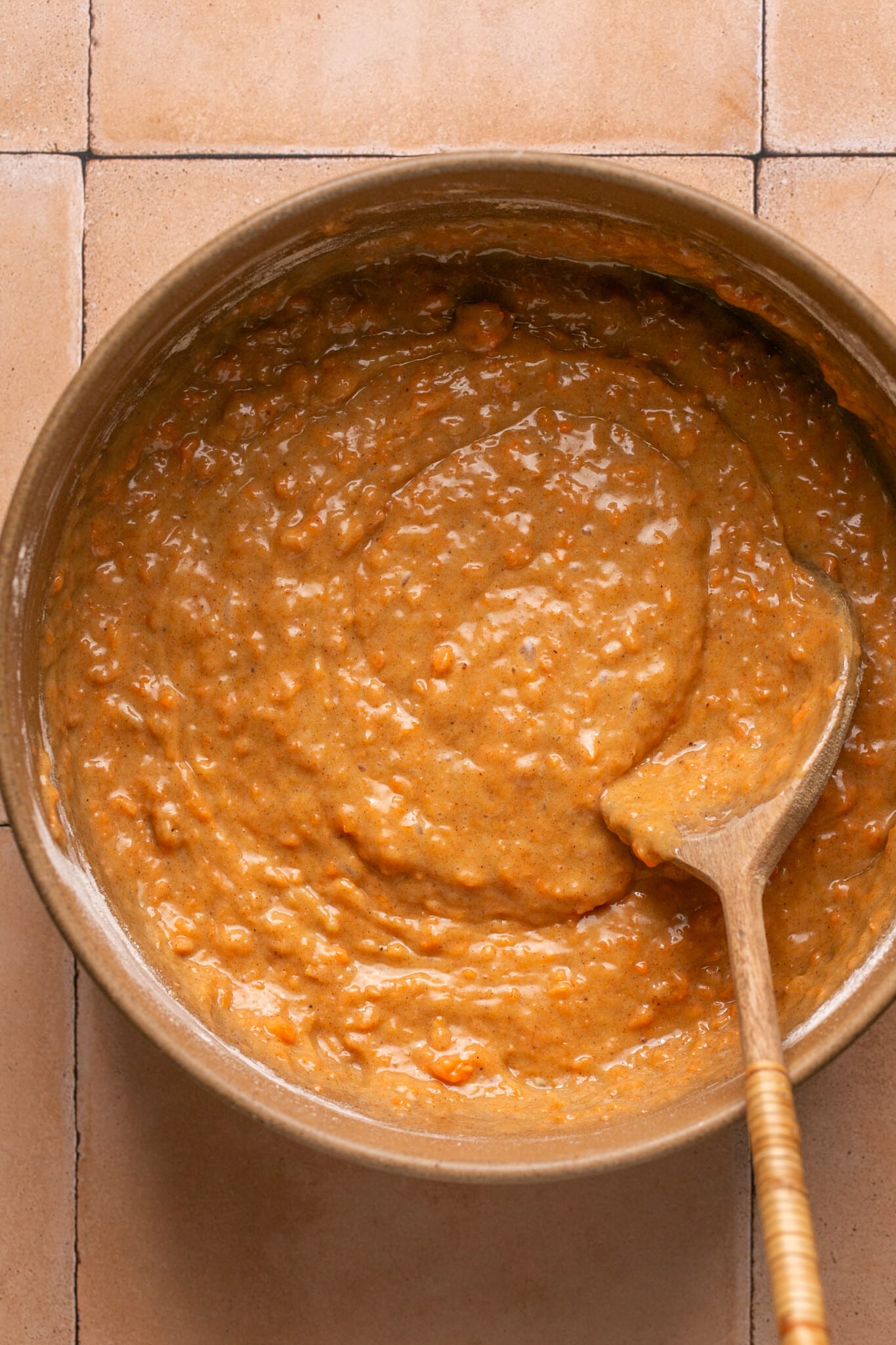 carrot cake batter in a mixing bowl with a wooden spoon. 
