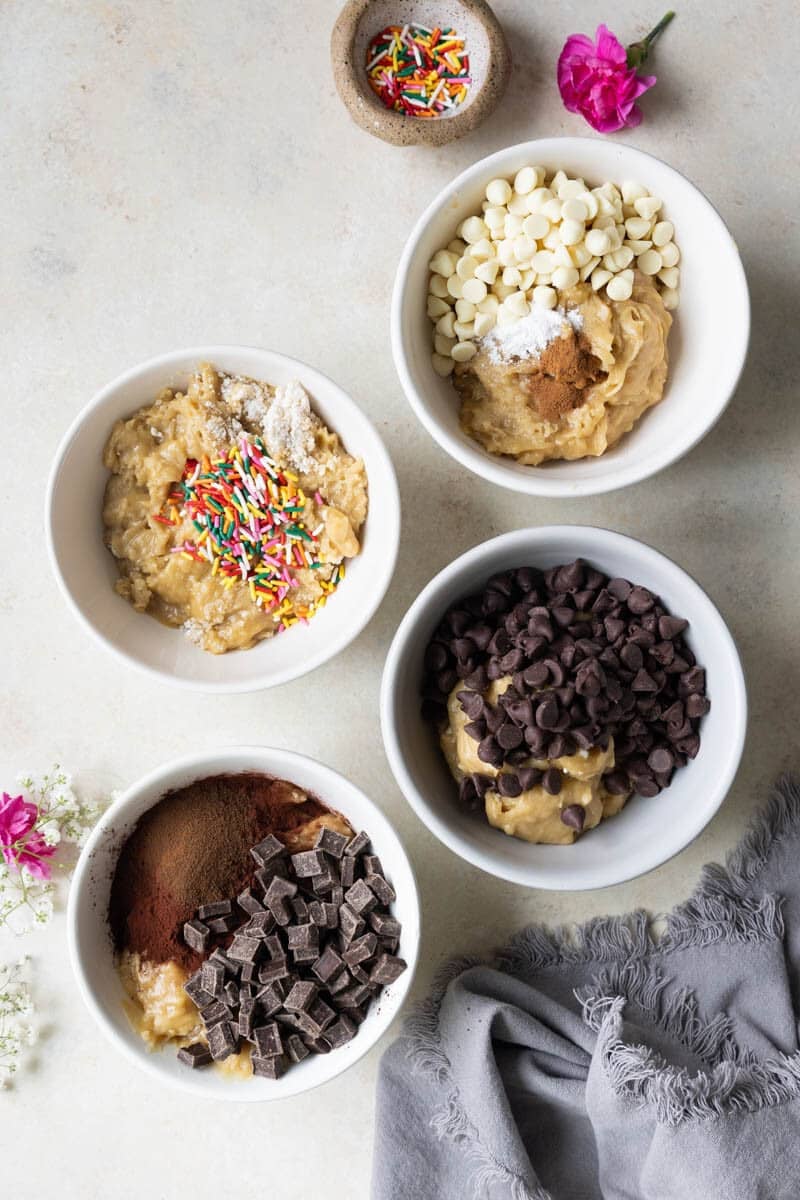 4 different cookie doughs in white bowls.