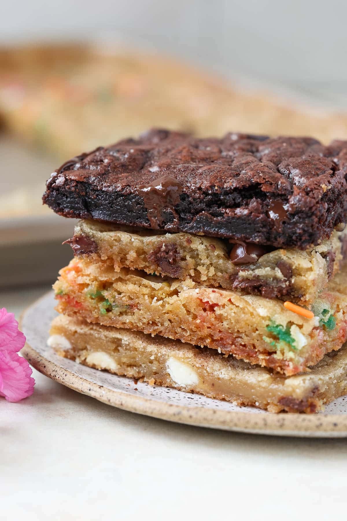 a stack of 4 different flavor cookie bars on a plate.