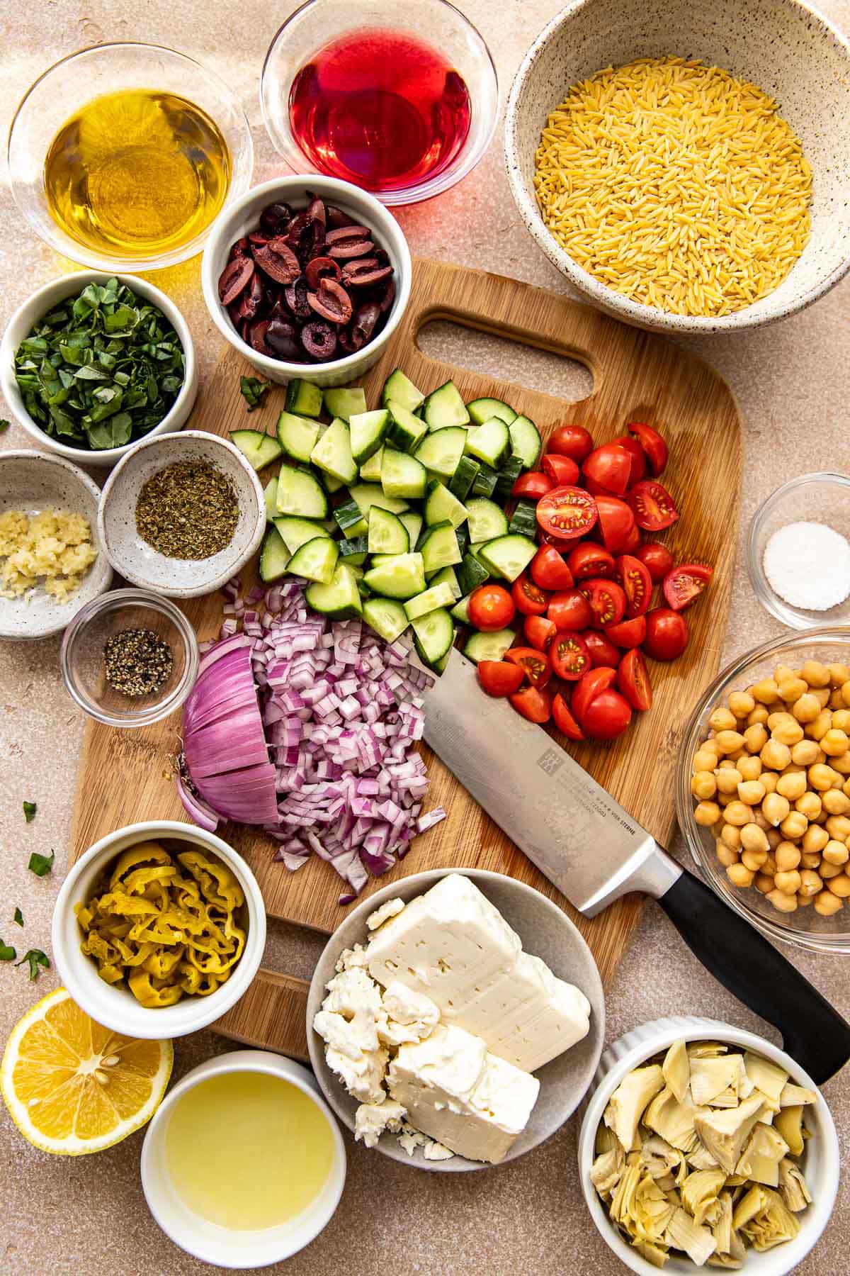ingredients to make orzo salad on a cutting board. 