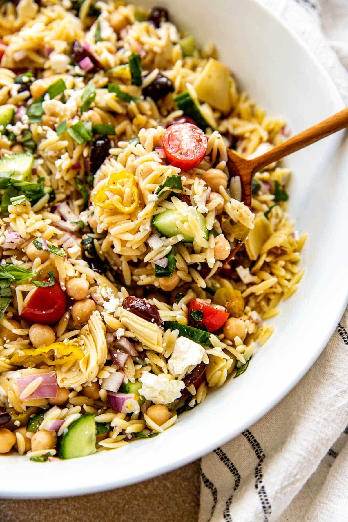 a spoon scooping out some orzo salad. 