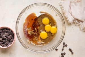 eggs and vanilla extract added to a glass bowl for cookie dough.