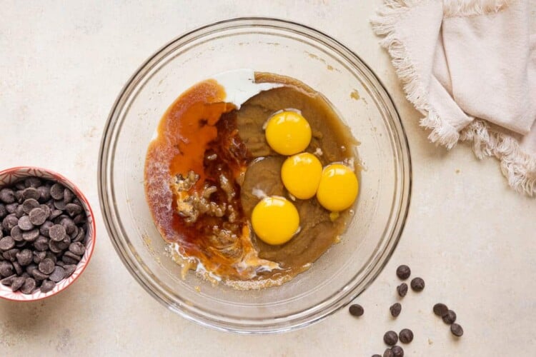 eggs and vanilla extract added to a glass bowl for cookie dough.