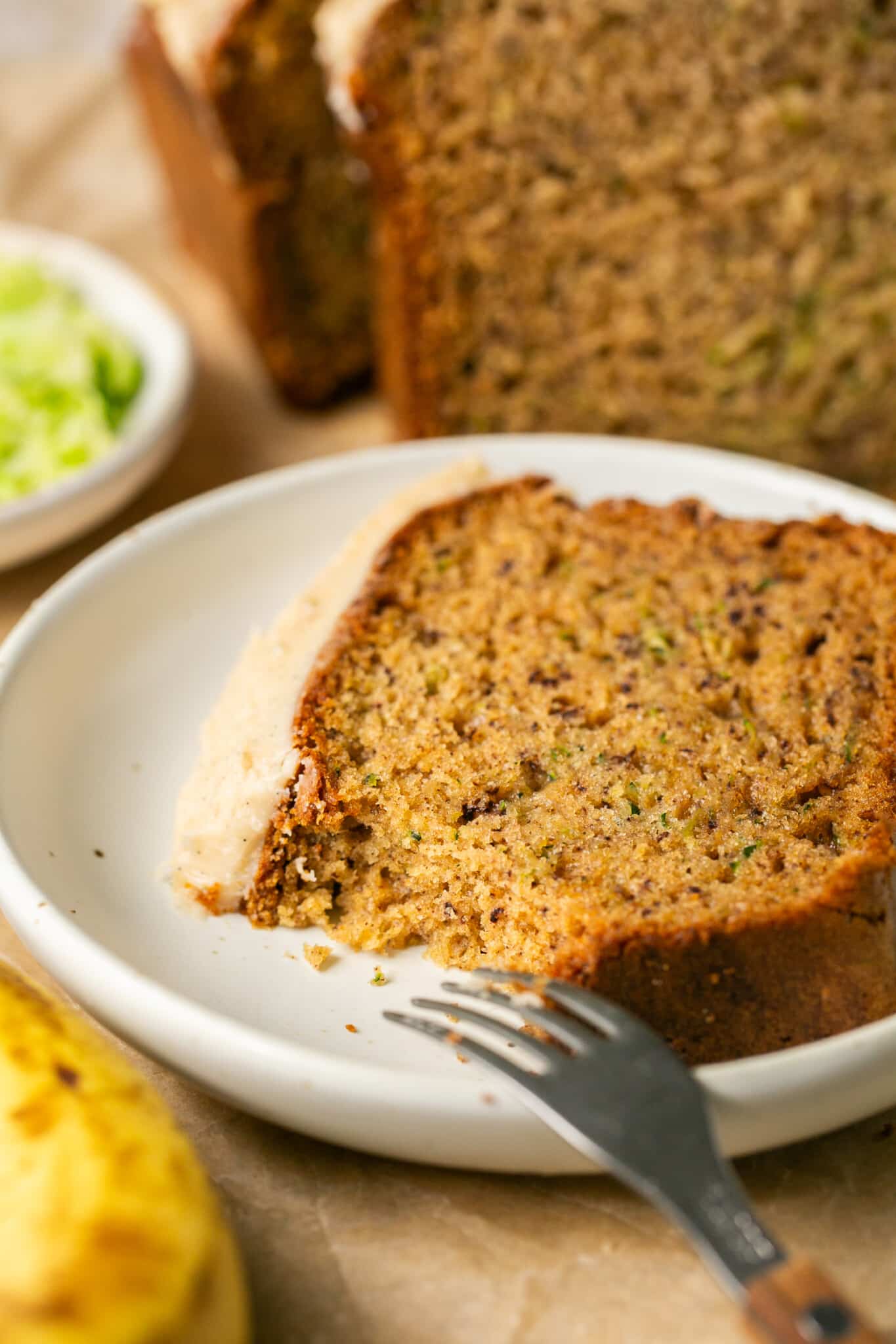 a bite taken out of a slice of zucchini bread thats on a white plate. 