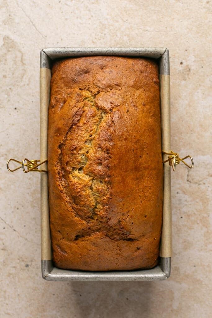 a freshly baked loaf of zucchini banana bread in a loaf pan. 