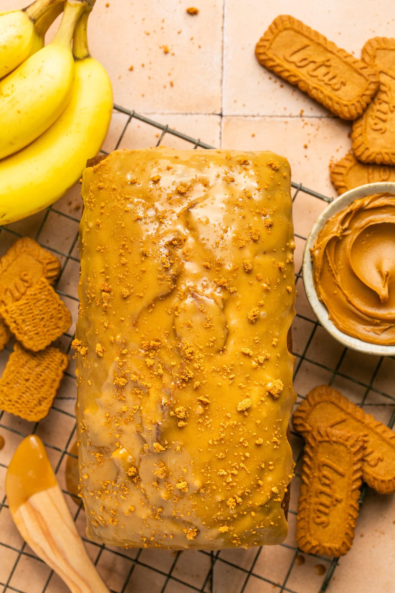 banana bread with a biscoff glaze on top on a wire cooling rack.