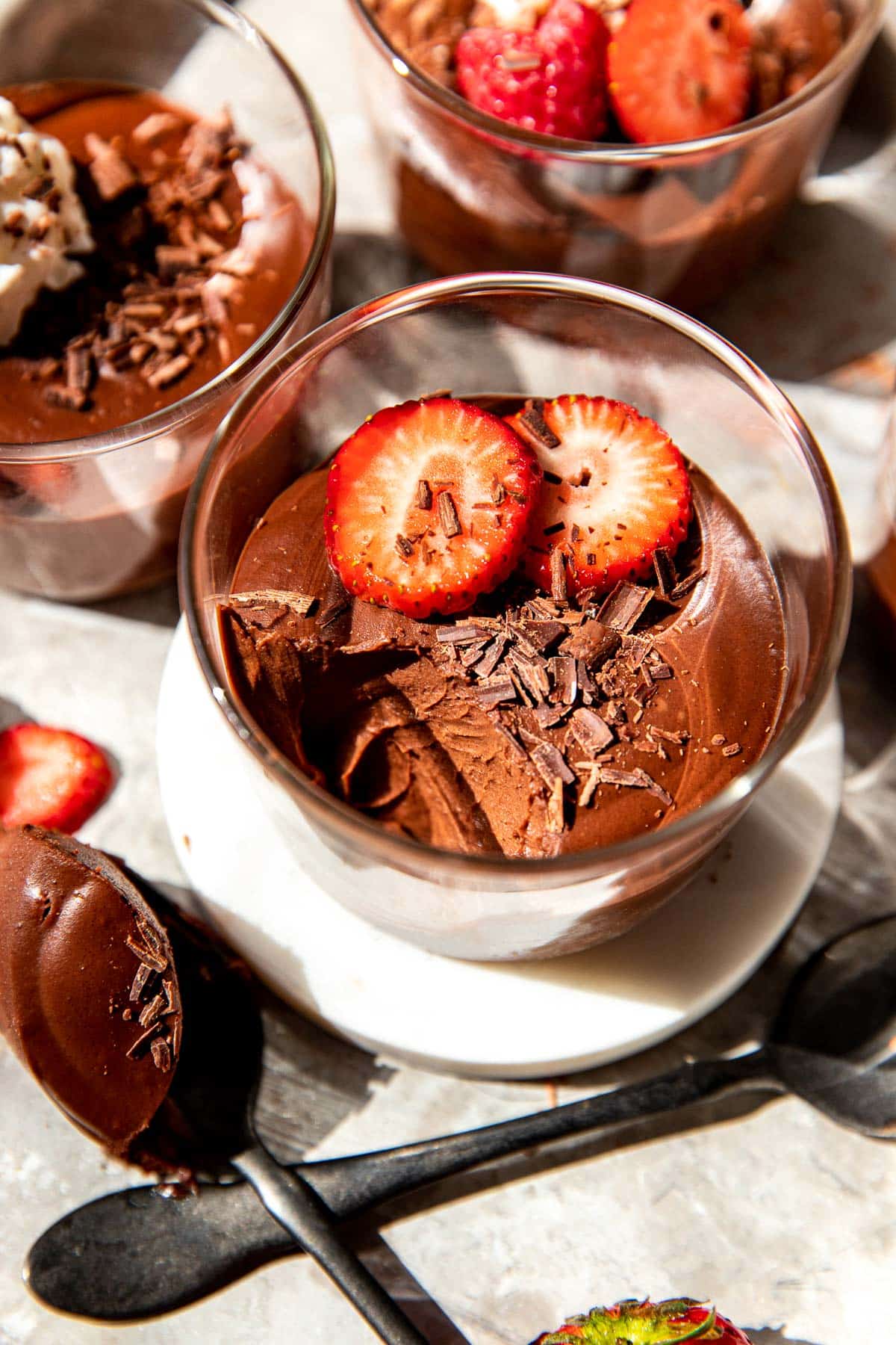 chocolate mousse in glass cups with fruit and chocolate shavings on top. 