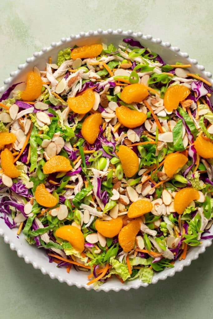 chicken salad in a bowl with mandarines and almonds on top.
