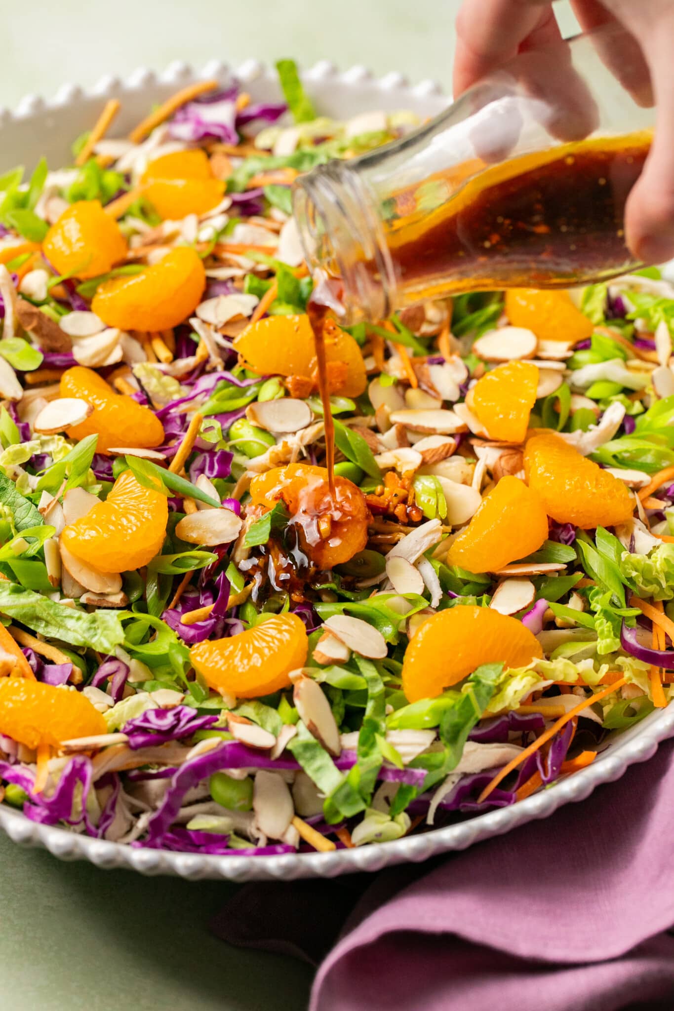 dressing being poured on top of a salad.