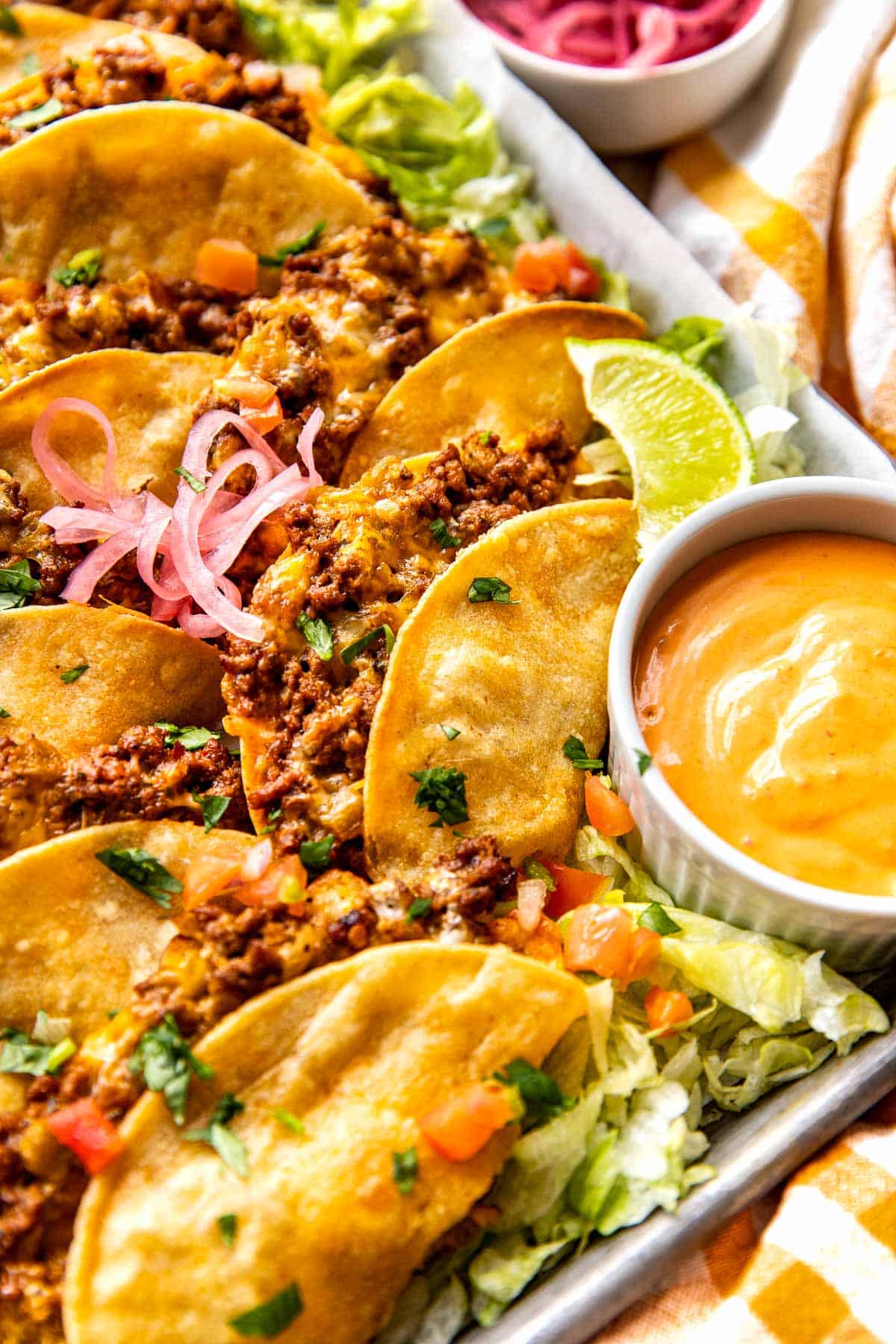 tacos on a sheet pan garnished with cilantro and red onions. 