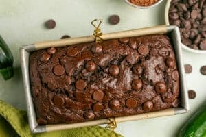 a freshly baked loaf of zucchini bread in an aluminum loaf pan lined with parchment paper.