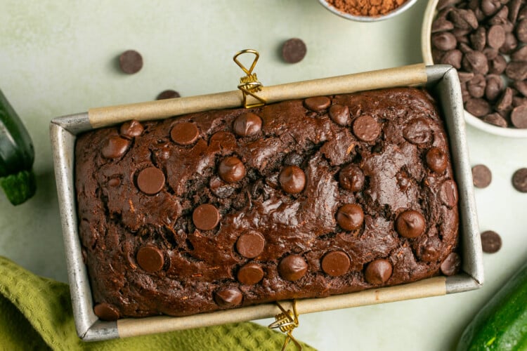 a freshly baked loaf of zucchini bread in an aluminum loaf pan lined with parchment paper.