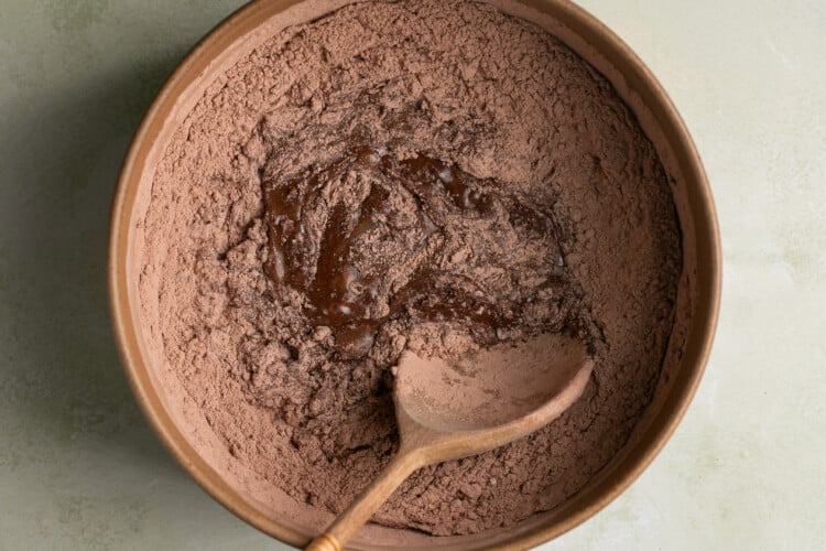 a wooden spoon stirring in dry ingredients into zucchini bread batter.