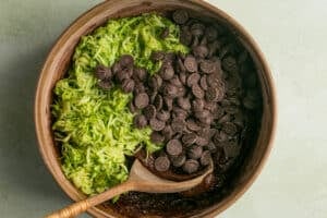 grated zucchini and chocolate chips in a wooden bowl for zucchini bread.
