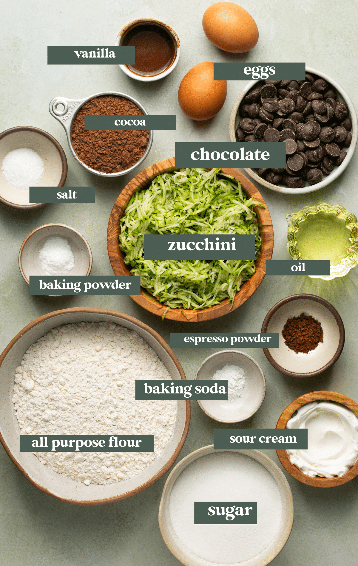 ingredients to make zucchini bread in small glass and wooden bowls. 