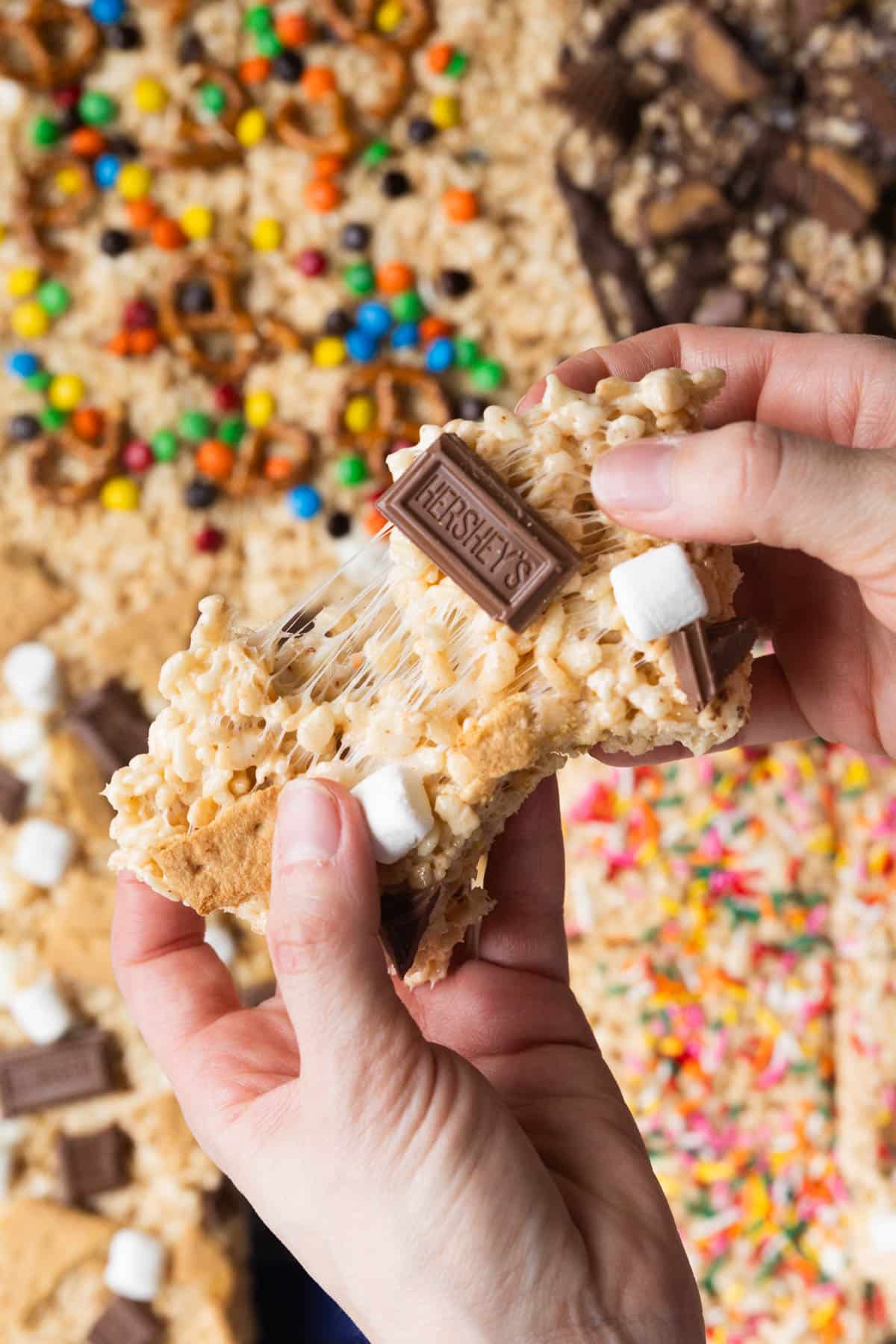 a womans hands pulling apart rice krispie treat. 