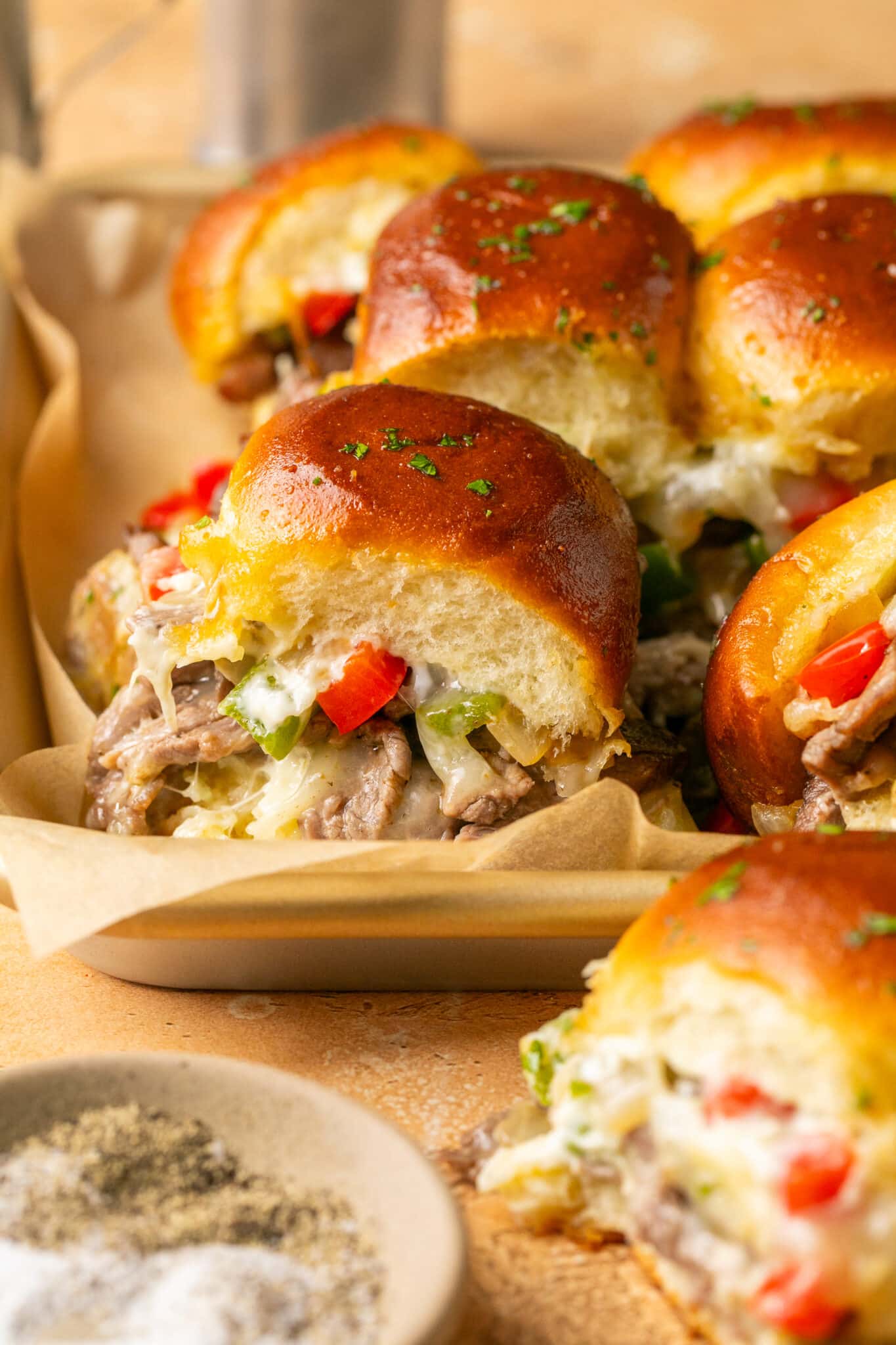 philly cheesesteak sliders on a baking cheese lined with parchment paper.