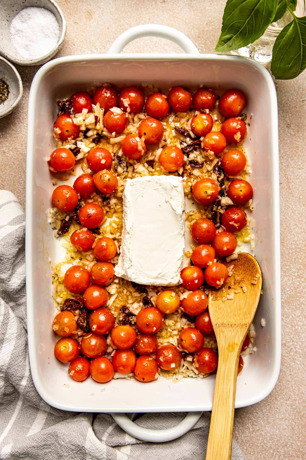 cherry tomatoes, onions, and cream cheese in a white casserole dish.