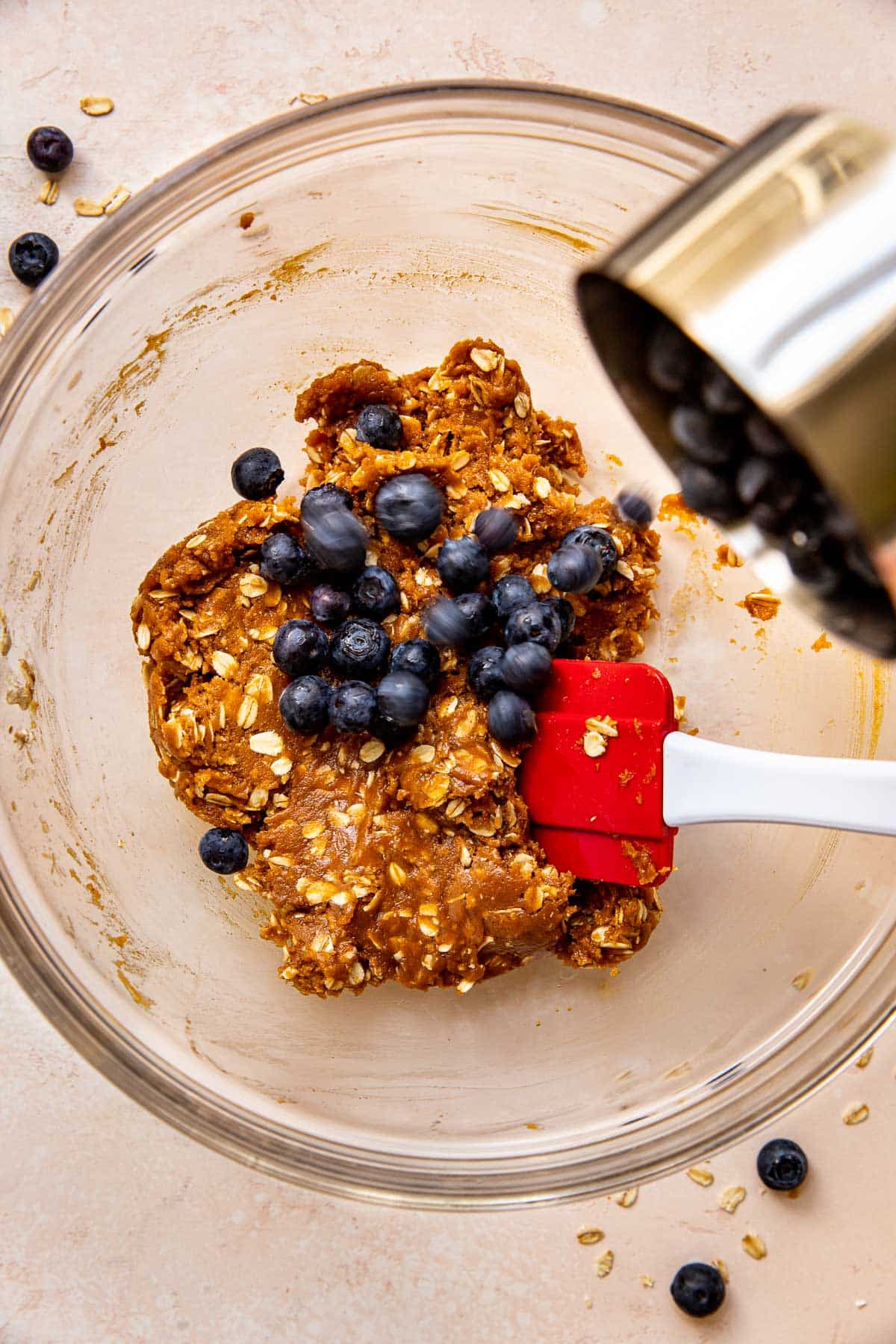 blueberries being poured into cookie dough.