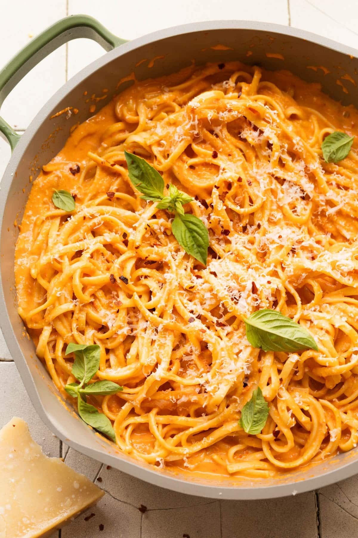 up close image of pasta with roasted bell peppers, parmesan and basil on top. 