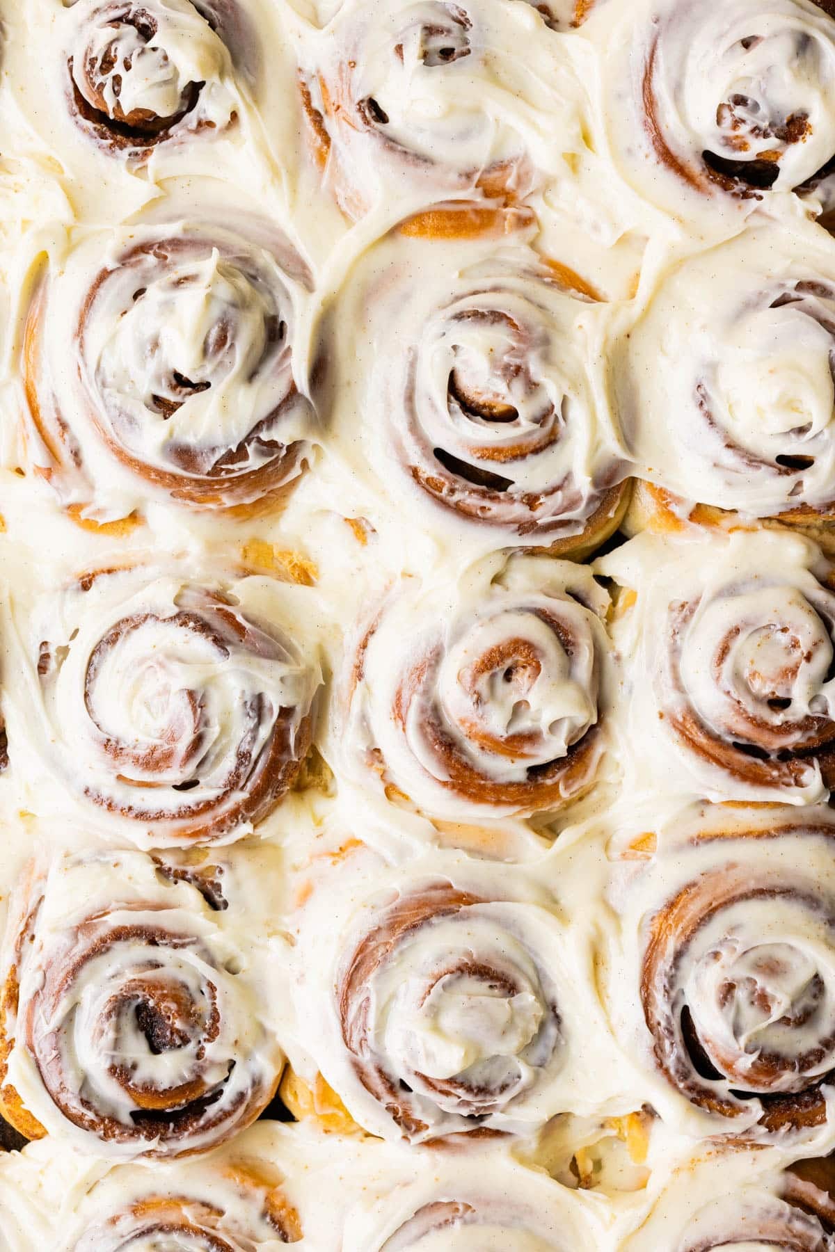 close up image of freshly baked cinnamon rolls with frosting on top. 