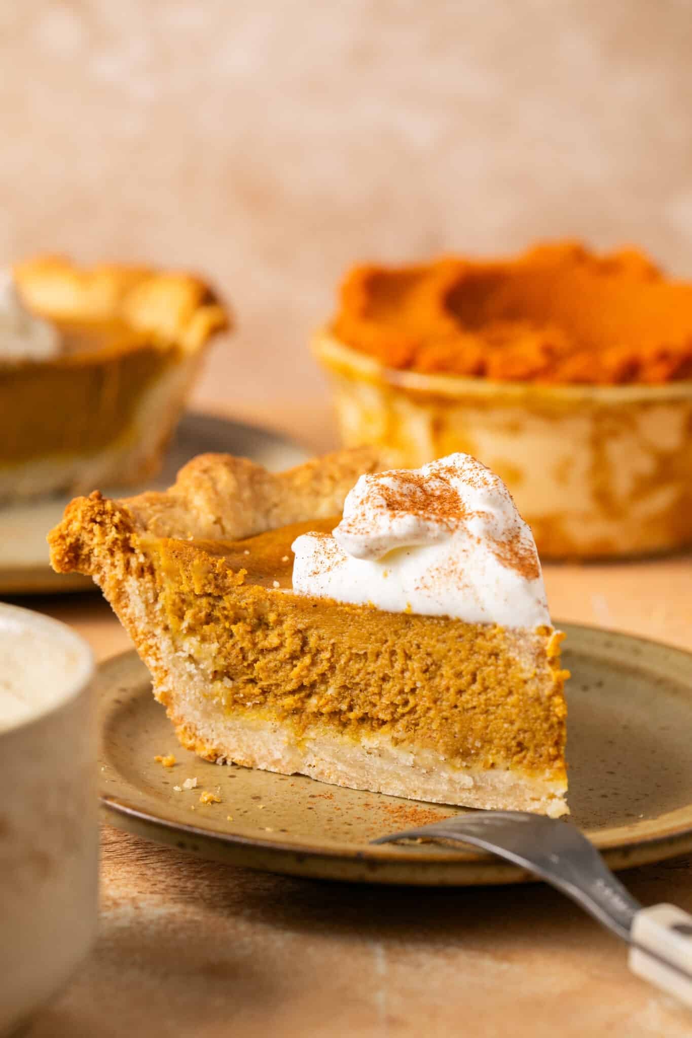 a slice of pumpkin pie on a brown plate. 