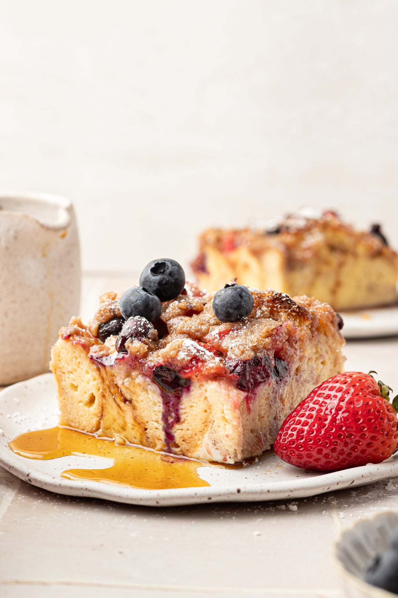 Slice of french toast with strawberries and blueberries with a drizzle of syrup.