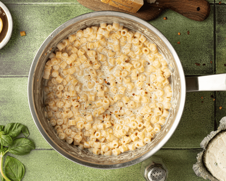 Image of boursin pasta in stainless steel pot once it has started to thicken as it cools down. Pasta is garnished with chili flakes.