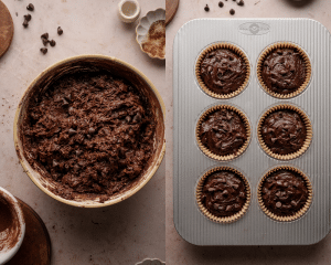 Side-by-side image of batter mixed for chocolate muffins then poured into jumbo muffin tins lined with parchment paper liners.