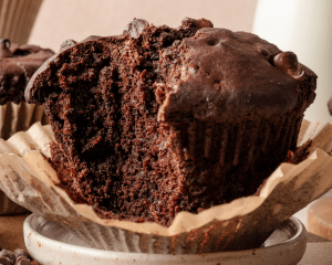 Upclose shot of chocolate muffin on plate with bite taken out.