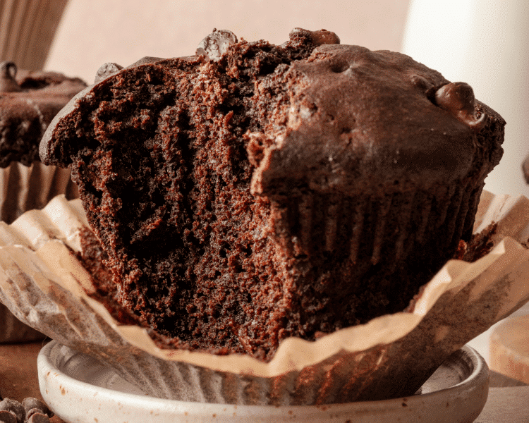 Upclose shot of chocolate muffin on plate with bite taken out.