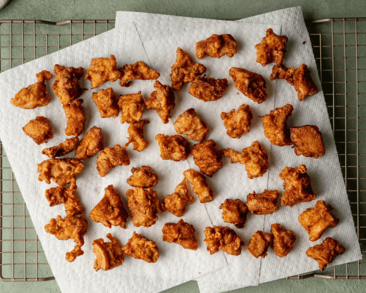 Image showing pieces of fried chicken cooling on wire rack lined with paper towels.
