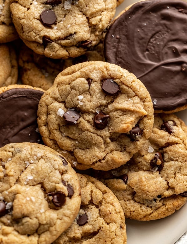 Plate of chocolate chip cookies dipped in chocolate with some of the cookies turned over so you can see the chocolate side.