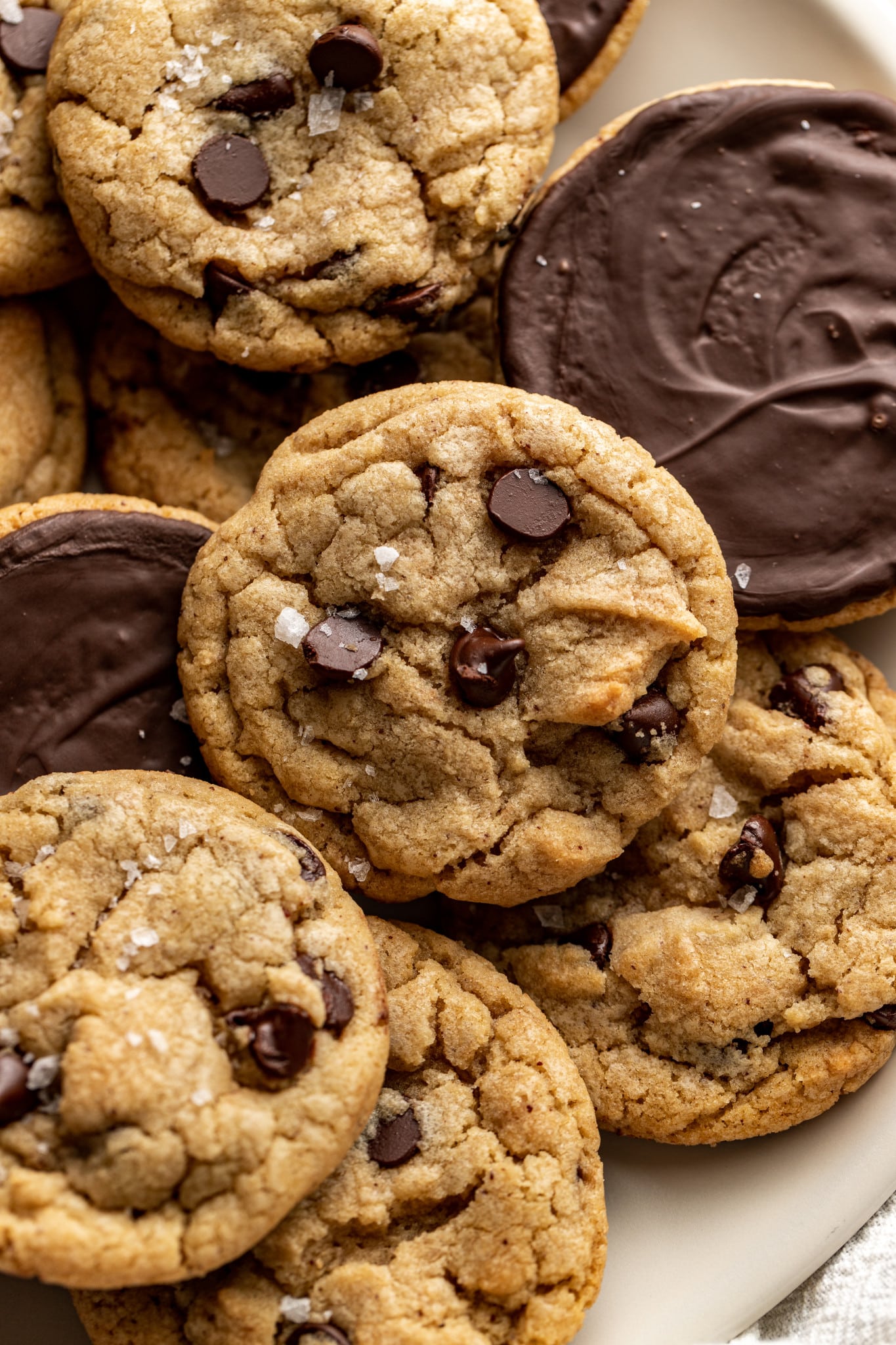 Plate of chocolate chip cookies dipped in chocolate with some of the cookies turned over so you can see the chocolate side.