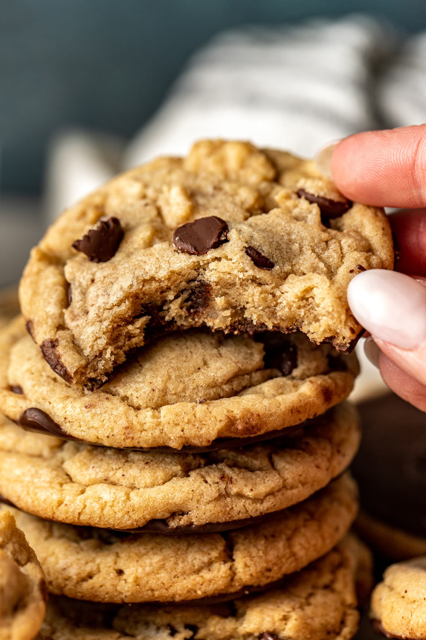 Stack of chocolate dipped chocolate chip cookies with the top cookie having a bite taken out of the middle.