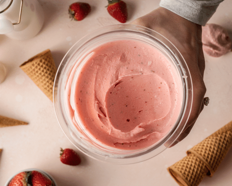 Strawberry ice cream in a ninja creami pint container with spoonful taken out.
