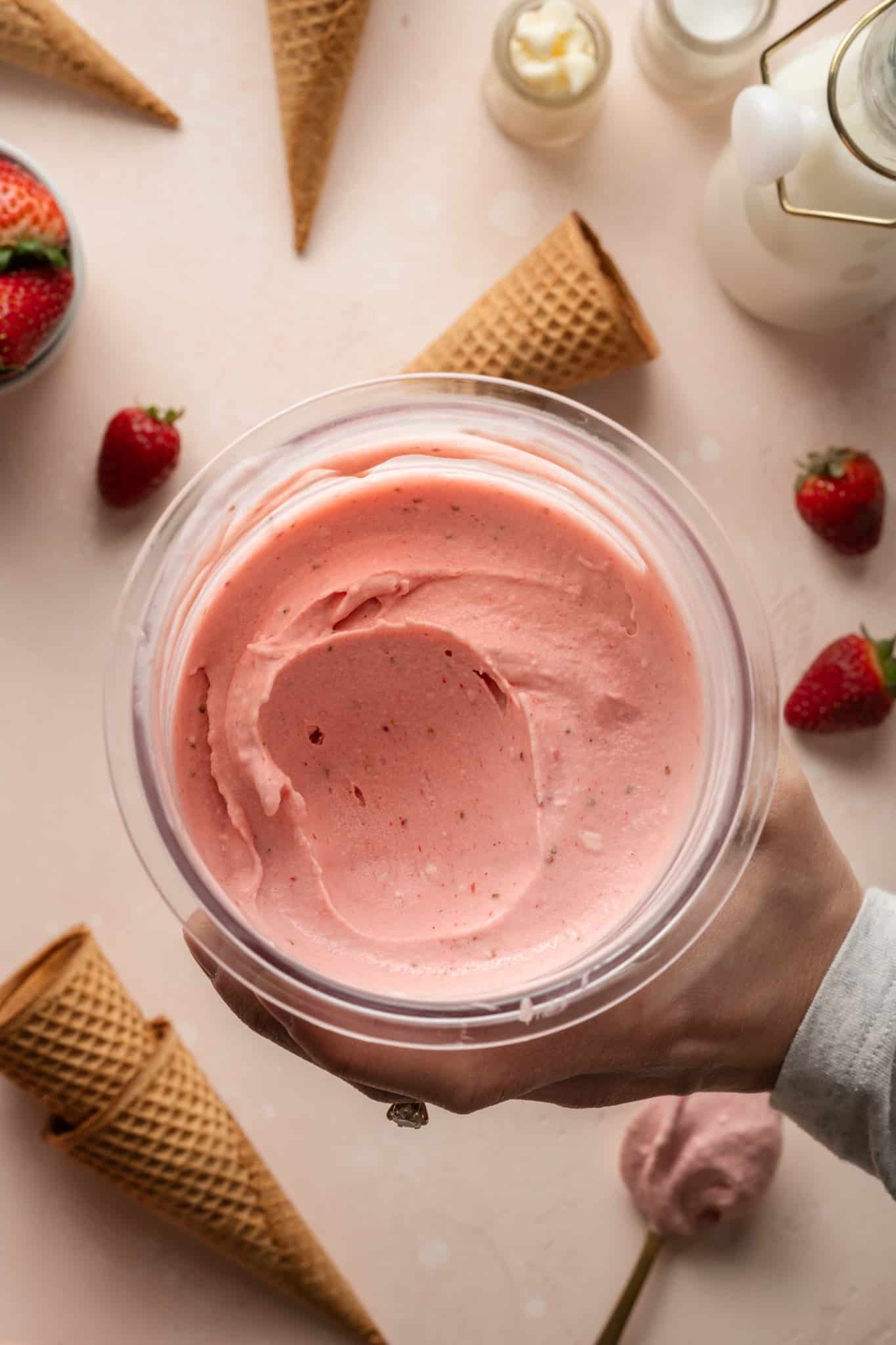 Strawberry ice cream in a ninja creami pint container with spoonful taken out.