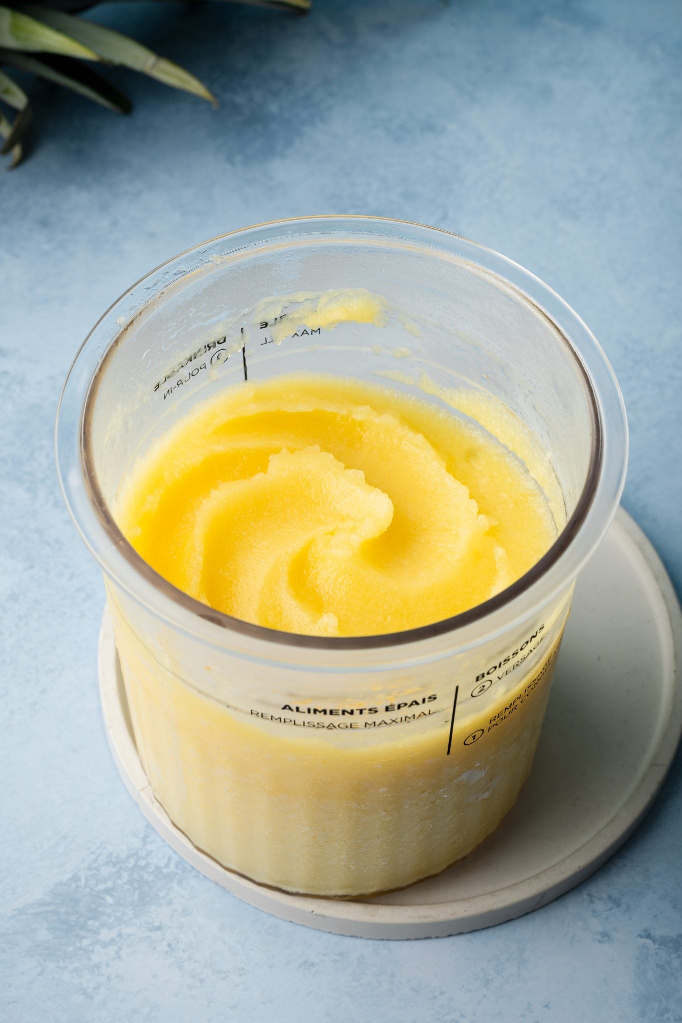 pineapple sorbet swirled in a ninja creami pint cup on a white plate. 