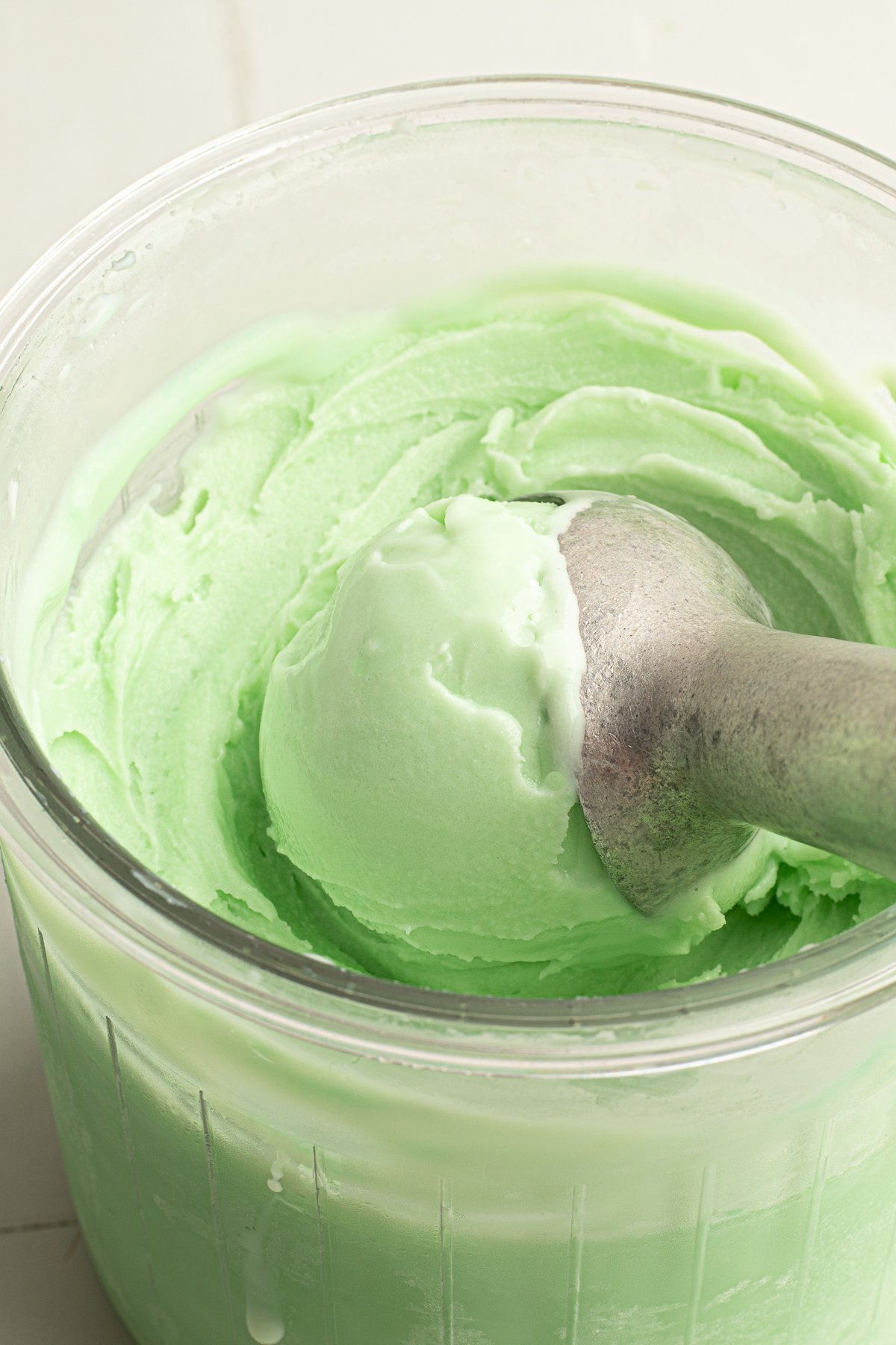 Close-up of a scoop of mint chocolate chip ice cream in the Ninja CREAMi pint, showing the smooth texture and light green color after spinning.