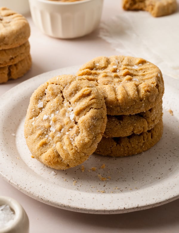 A stack of three peanut butter cookies on a plate with a fourth cookie stacked vertically against them.