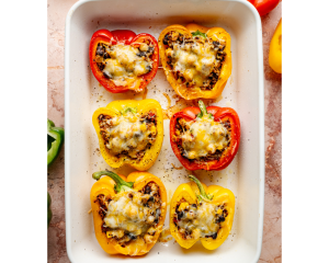 Baked quinoa stuffed bell peppers in a white baking dish, topped with melted golden-brown cheese and ready to serve.