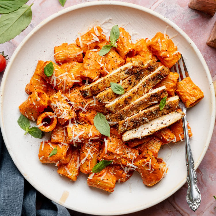 Spicy voda pasta with chicken on white plate with fork.