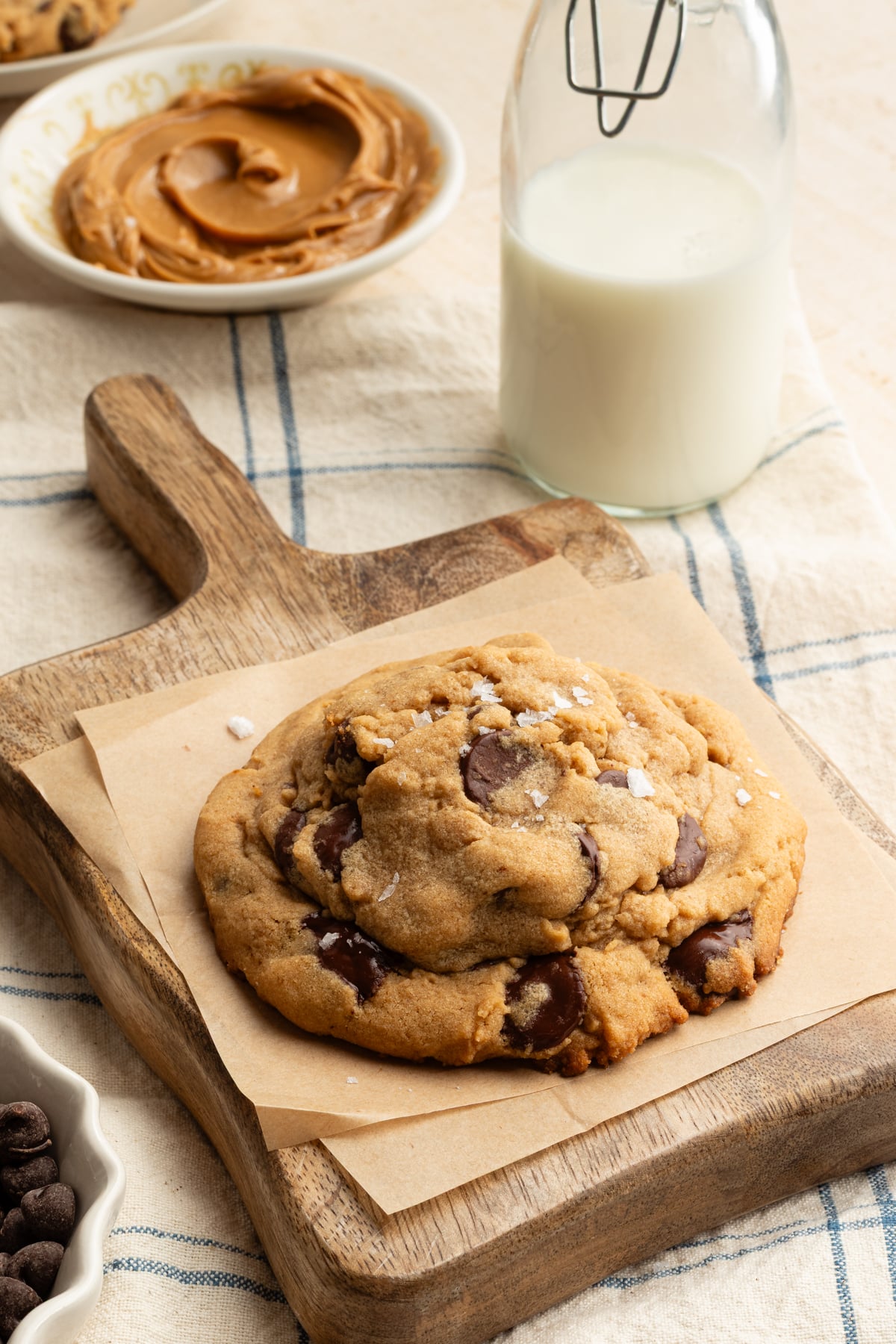 Giant peanut butter chocolate chip cookie on wooden serving platter.