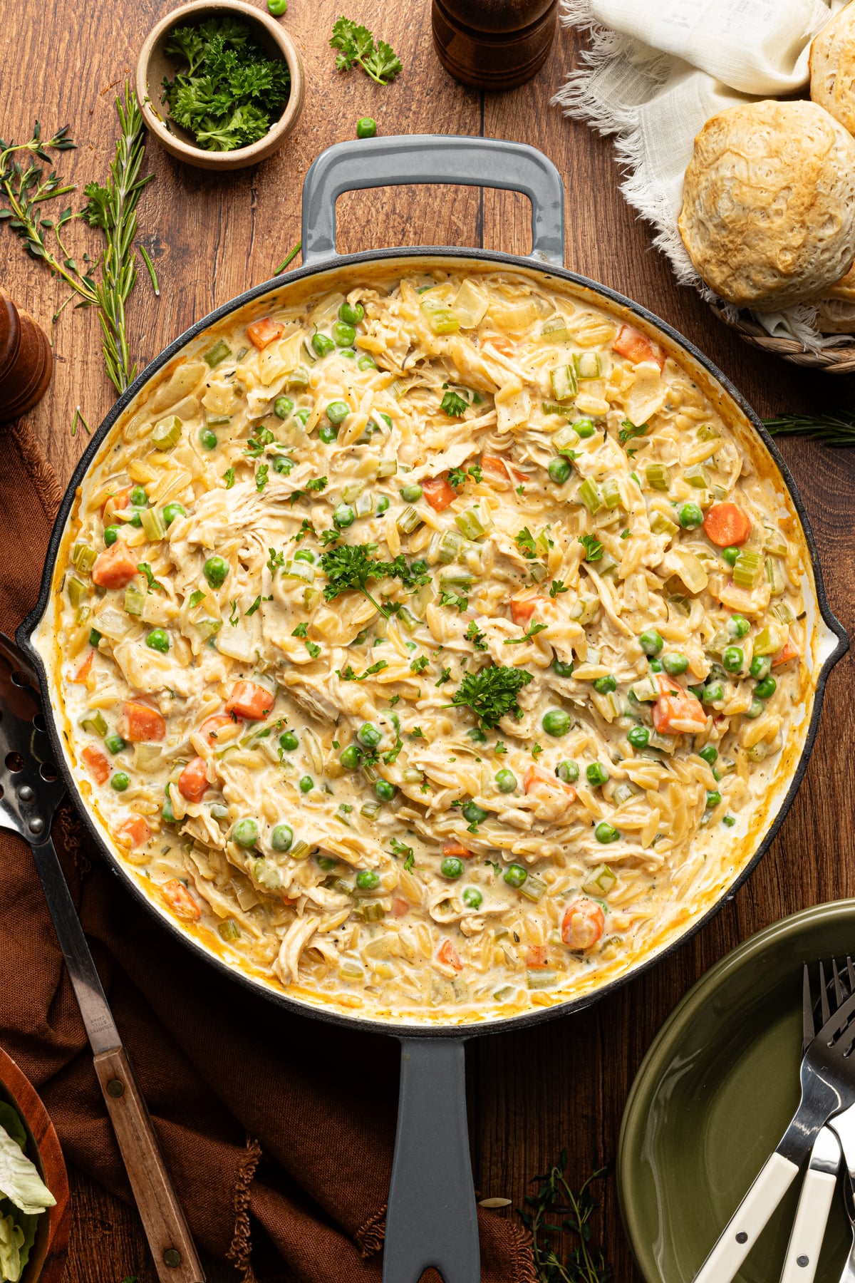 Chicken pot pie orzo cooked in a deep skillet and garnished with fresh parsley.