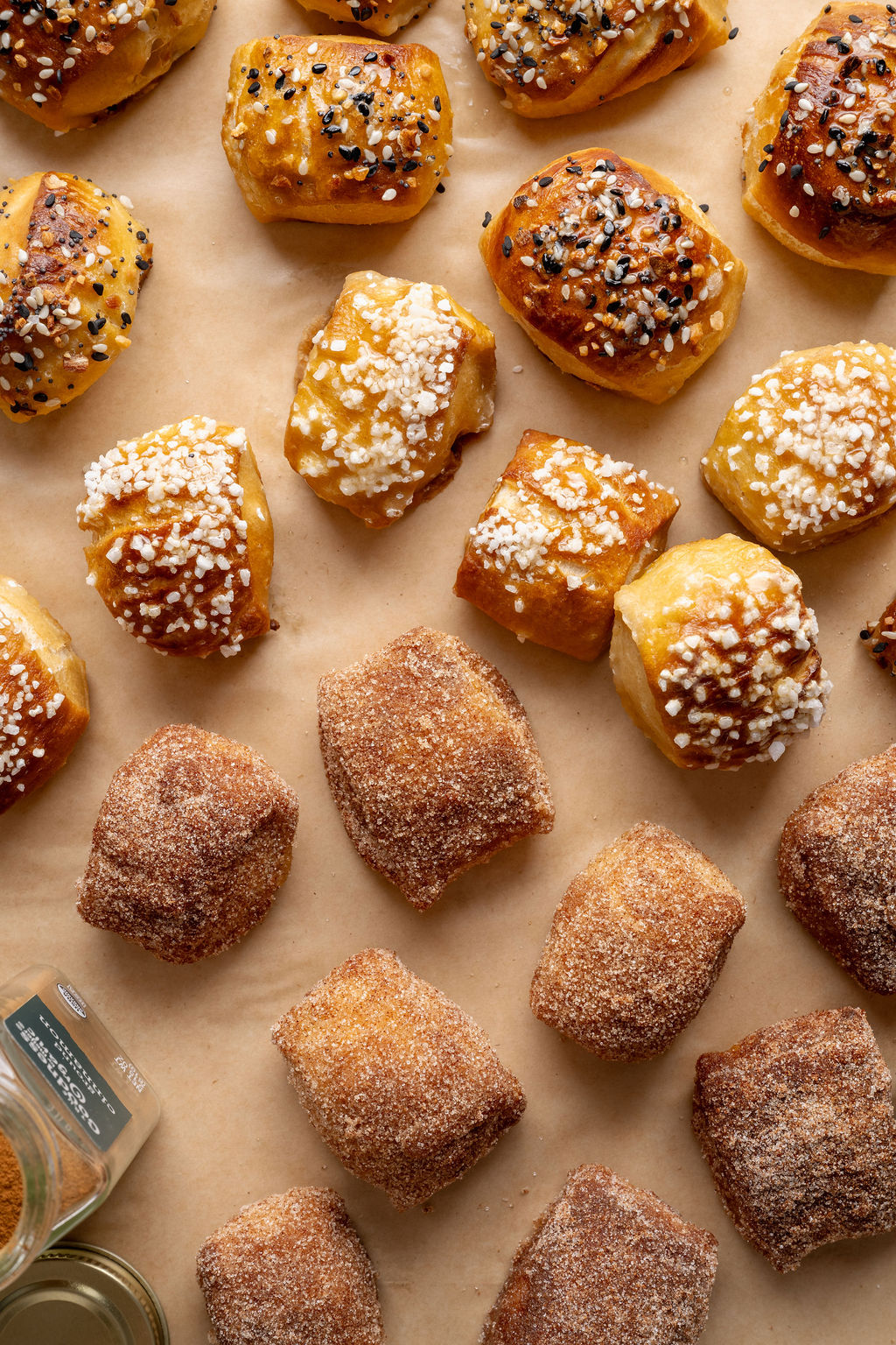 Close-up overhead view of golden pretzel bites topped with pretzel salt and everything bagel seasoning on a parchment-lined baking sheet.